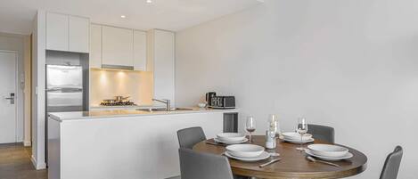 A modern kitchen with a central island, a dining table with chairs, and a small kitchenette area.