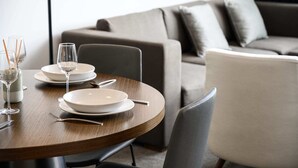 A dining area with a round table set for two, a sofa in the background, and a modern interior design. - Prime Location 1BD Apartment in Chatswood (Chatswood)