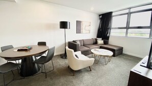 A modern living room with a round dining table, a sofa, and a coffee table.