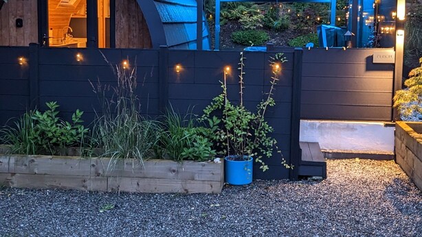 A rustic wooden cabin with a sloped roof, a wooden deck, and a small porch area. - Luxury Glamping Escape - Hot tub - West Coast Scotland (Innellan)