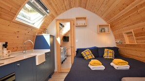 A cozy, wooden cabin-style bedroom with a large bed, a built-in desk, and a skylight.