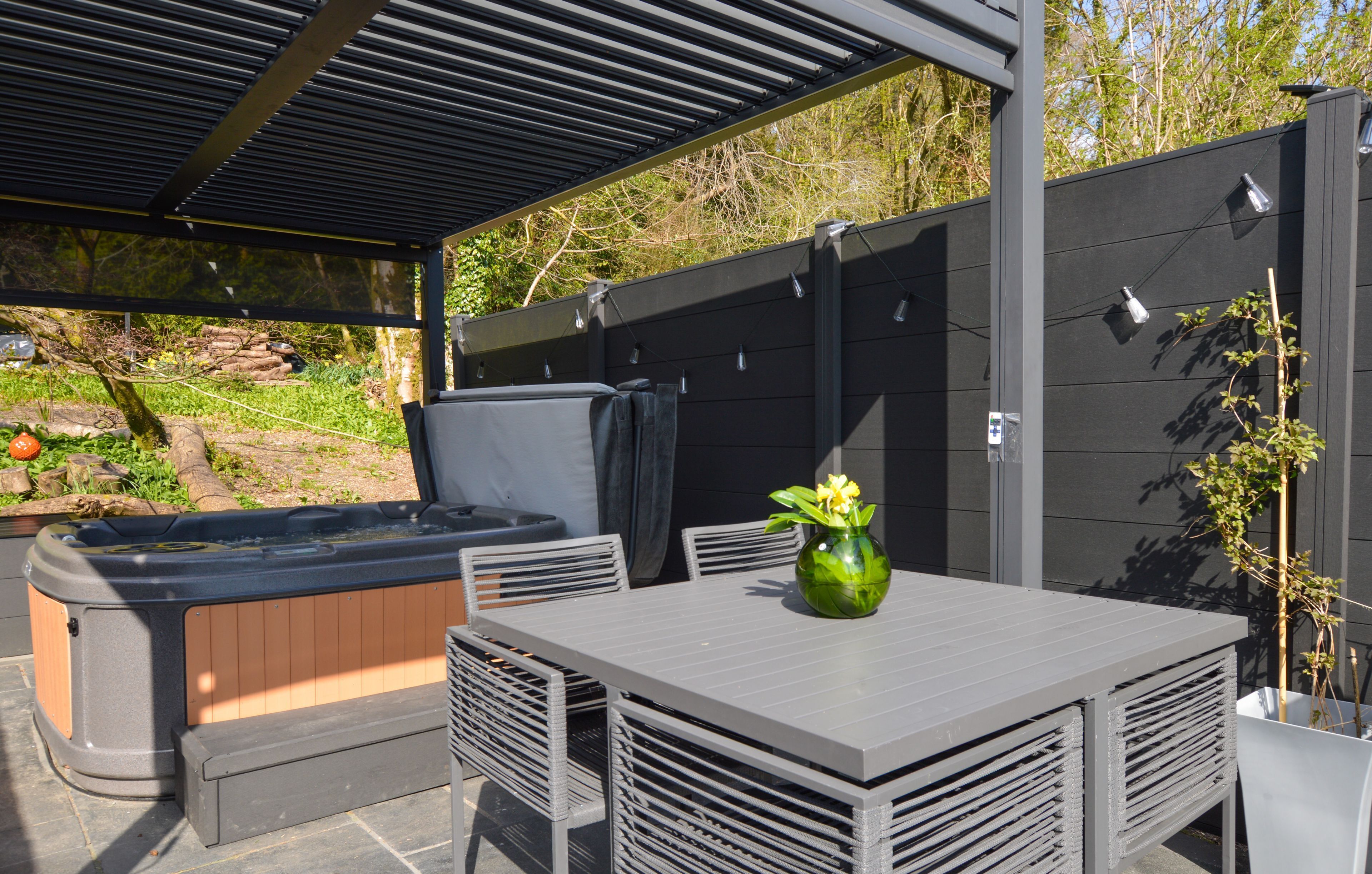 Un espace extérieur aménagé, abrité et doté d’une table, de chaises et d’un jacuzzi.