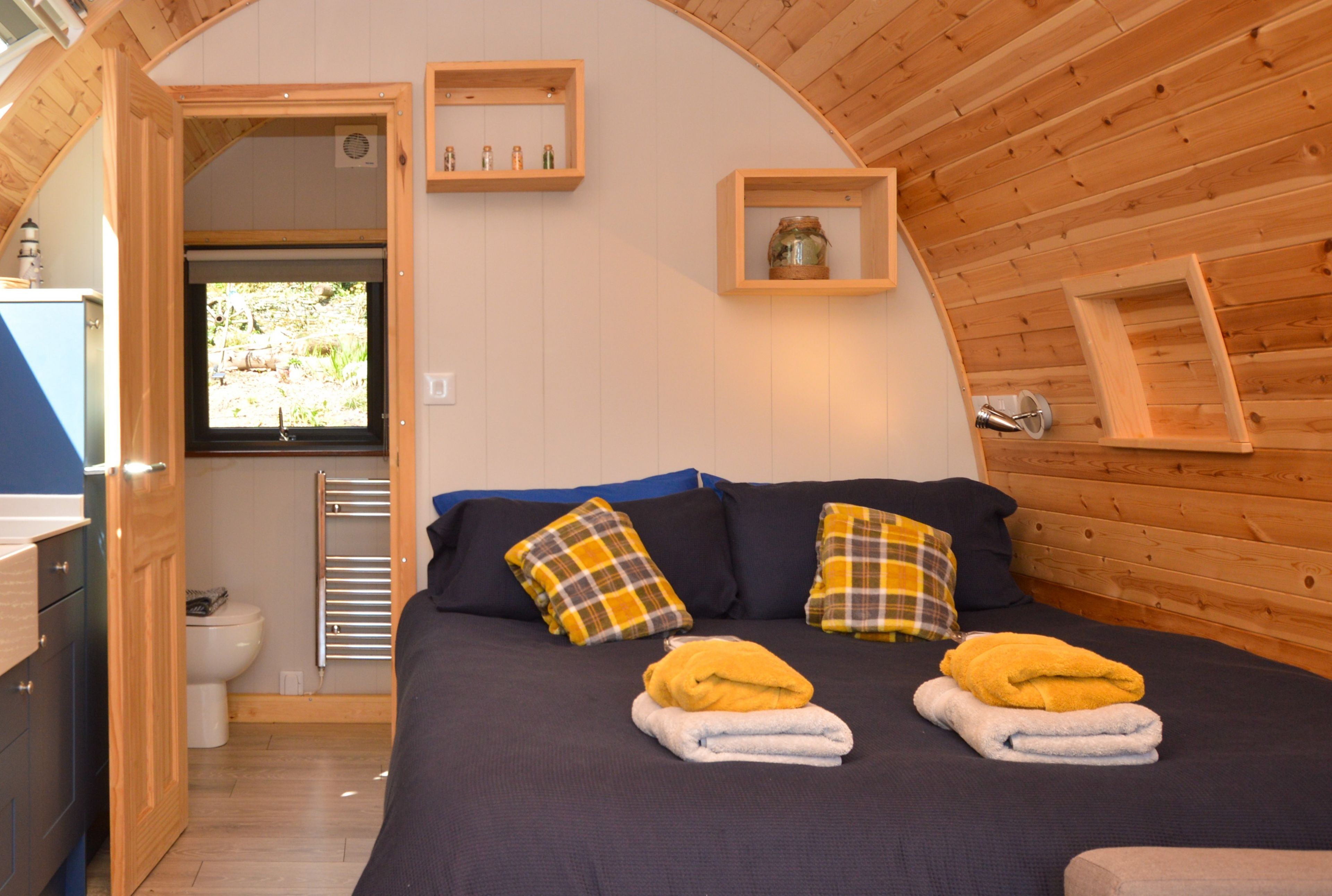 A cozy room with a bed, two pillows, a window, and a wooden ceiling.