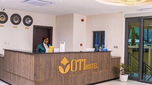 A hotel reception desk with a logo, a receptionist, and a modern interior design. - OTI Hotel Benin  (Benin City)