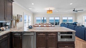 A spacious kitchen with dark wood cabinets, a marble countertop, and a built-in oven. - Bird of Paradise: Beachfront Views, Multiple Living Areas, Pet-Friendly (Mexico Beach)