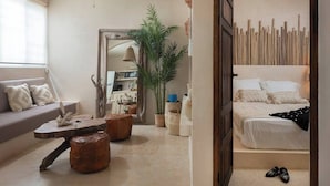 A modern bedroom with a bed, a seating area with a sofa, and a dining table.