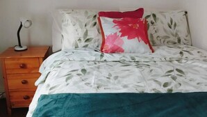 Een slaapkamer met een bed, nachtkastje en lamp.