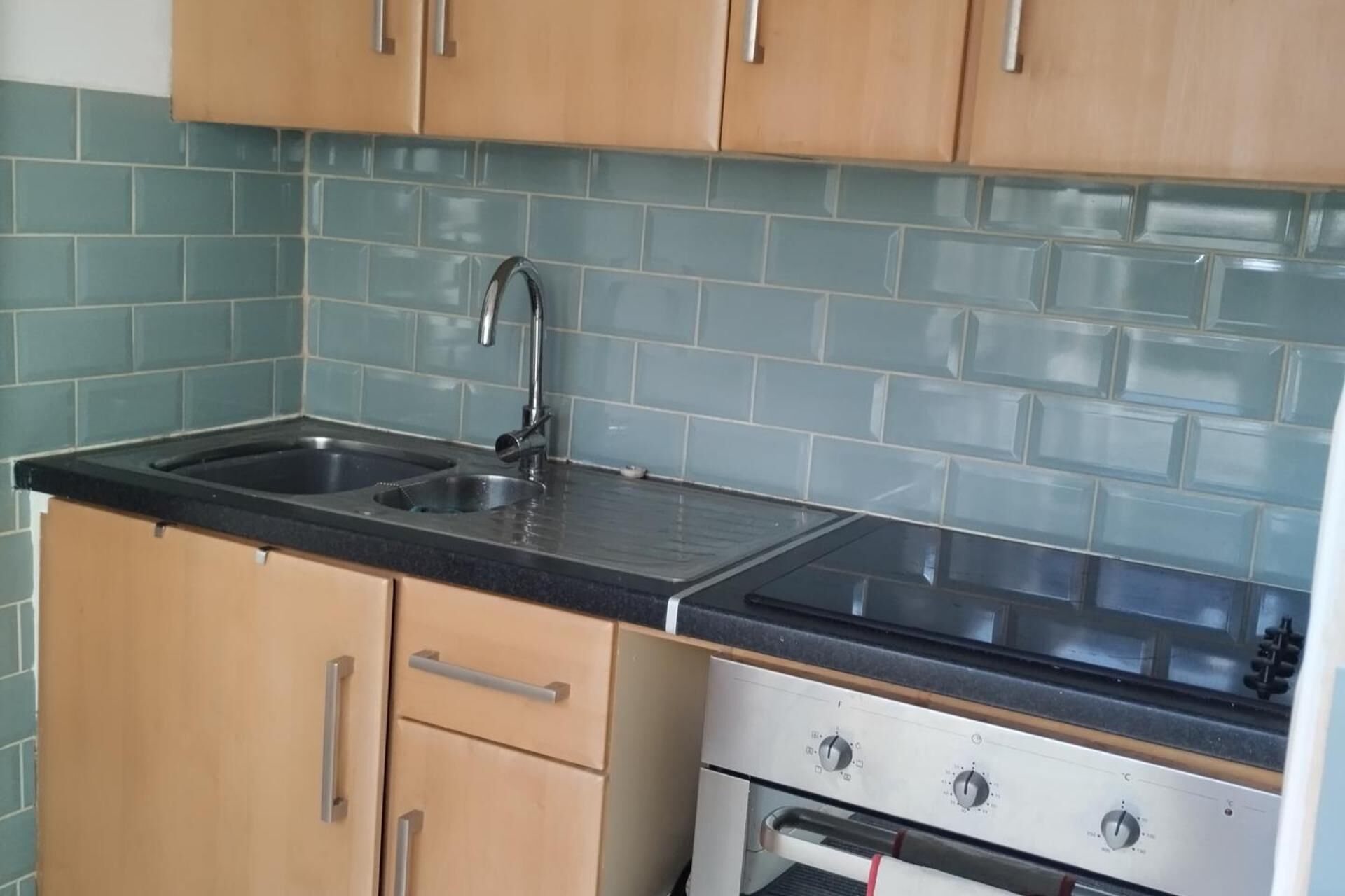 A kitchen with two sinks, wooden cabinets, and a stainless steel oven.