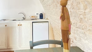 Une cuisine rustique avec un mur en pierre, des armoires en bois et un petit réfrigérateur.