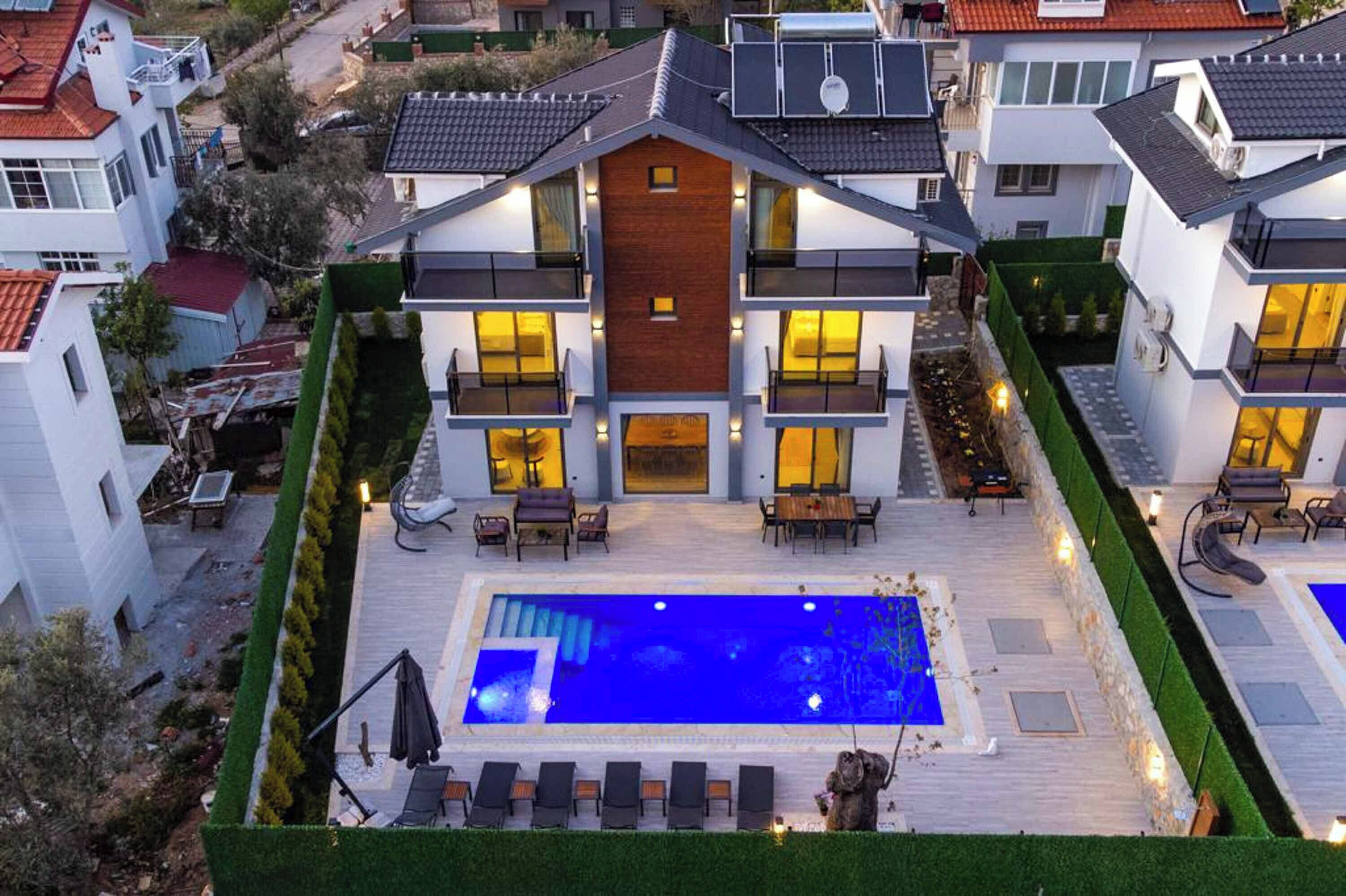 A modern two-story house with a swimming pool, outdoor seating, and a well-maintained garden.