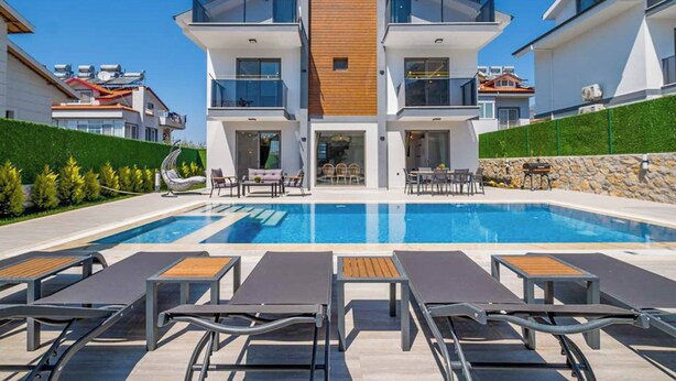Uma casa moderna de dois andares com piscina em frente.