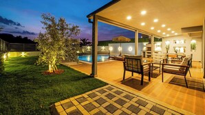 Un patio exterior con piscina, mobiliario y iluminación ambiental.