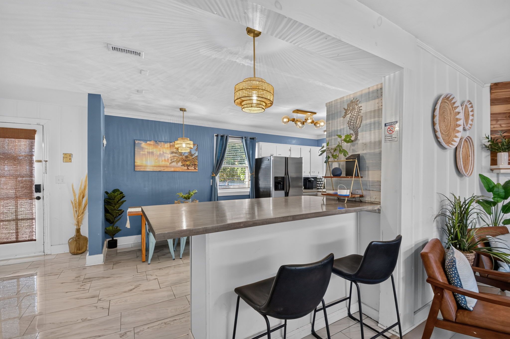 Una cocina moderna con barra, electrodomésticos de acero inoxidable y una pared azul.
