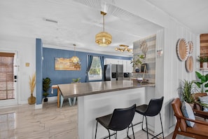 Une cuisine moderne dotée d’un coin bar, d’appareils électroménagers en acier inoxydable et d’un mur d’accent bleu.