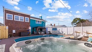 A backyard with a hot tub, a swimming pool, and a patio area with outdoor furniture. - Coastal home w/ pool, hot tub & fire pit (Norfolk)
