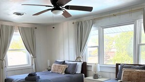 A bedroom with two beds, a ceiling fan, and large windows. - Coastal home w/ pool, hot tub & fire pit (Norfolk)