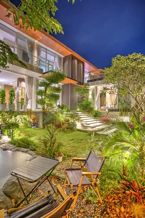 A modern building with a well-maintained garden, outdoor seating, and a pool.