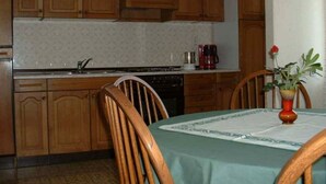 A kitchen with wooden cabinets, a sink, a stove, and a dining table with chairs. - Apartman Žardin with AC and balcony (Punat)