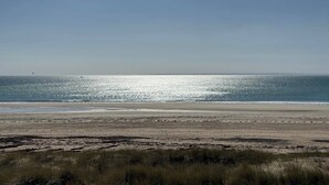 Una playa con cielo despejado y mar tranquilo.
