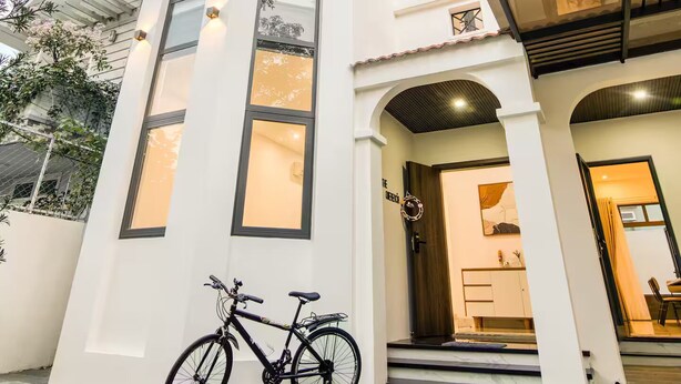 Un edificio blanco con un balcón y una bicicleta estacionada frente a él.