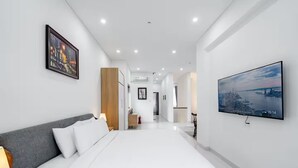 Una habitación de hotel moderna con una cama grande, un televisor de pantalla plana y vistas a la ciudad.
