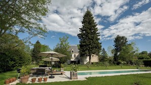 Ein Haus mit Swimmingpool, Terrassenmöbel und Topfpflanzen.