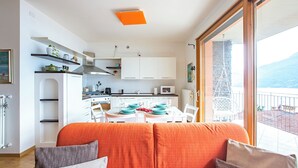 A compact living space with a kitchenette, dining area, and a balcony with a view.