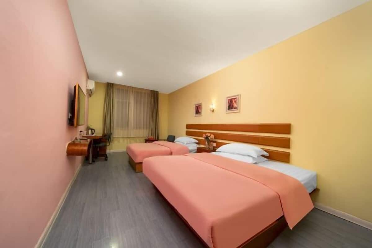 A hotel room with two beds, a desk, a chair, and a window with curtains.
