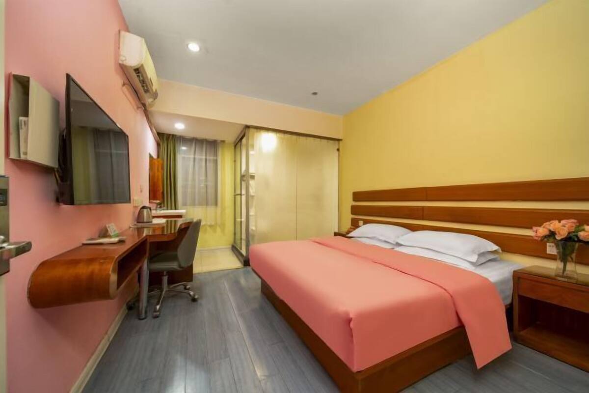 A hotel room with a bed, desk, chair, and a television.