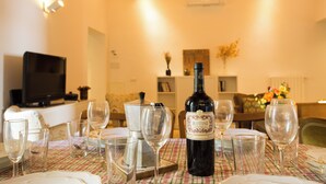 A dining table set with wine glasses and a bottle of wine, with a television and decorative items in the background. - Dimora Mattonaia: Cozy apartment with AC and WiFi (Firenze)