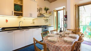 A kitchen with white cabinets, a black countertop, and a dining area with a table set for four. - Dimora Mattonaia: Cozy apartment with AC and WiFi (Firenze)