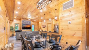 A wooden cabin interior with a dining area, kitchen, and living space. - Gorgeous 3BD Near Creek! Hot Tub + FirePit + Games (Sevierville)