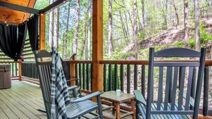 A wooden deck with a table and chairs, overlooking a forested area. - Gorgeous 3BD Near Creek! Hot Tub + FirePit + Games (Sevierville)