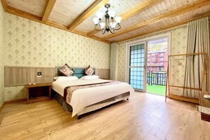 A bedroom with a wooden ceiling, a large bed with a white and brown bedspread, a nightstand, and a window with curtains.