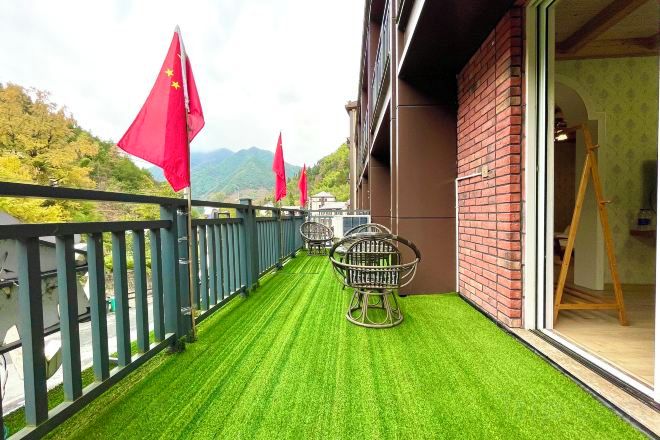 A balcony with artificial grass, a brick wall, and a view of mountains.