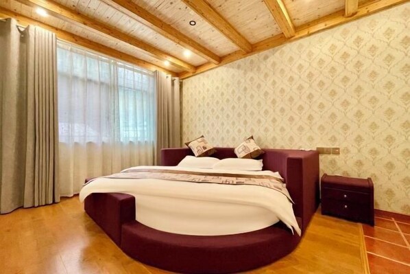 A bedroom with a curved bed, wooden ceiling beams, a patterned wallpaper, and a window with curtains. - Hangzhou Lin'an Daming Spring Inn (Daming Mountain) (Hangzhou)