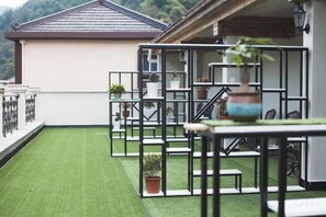 Eine Dachterrasse mit Kunstgrasanlage, Pflanzkübeln und Gartenmöbeln.