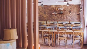 A restaurant with wooden tables and chairs, stone walls, and ceiling fans. - Hangzhou Lin'an Daming Spring Inn (Daming Mountain) (Hangzhou)