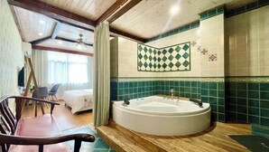 A room with a large bathtub, wooden flooring, a chair, and a bed. - Hangzhou Lin'an Daming Spring Inn (Daming Mountain) (Hangzhou)