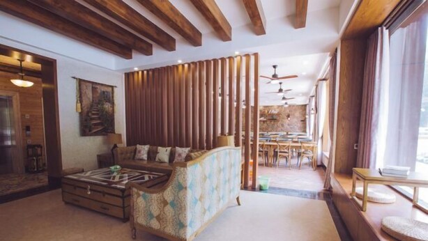 A spacious living room with a patterned sofa, wooden beams on the ceiling, a dining area in the background, and a large window on the right. - Hangzhou Lin'an Daming Spring Inn (Daming Mountain) (Hangzhou)
