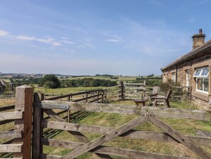 A rural landscape with a stone building, wooden fences, and a grassy field. - Folly View (Alnwick)