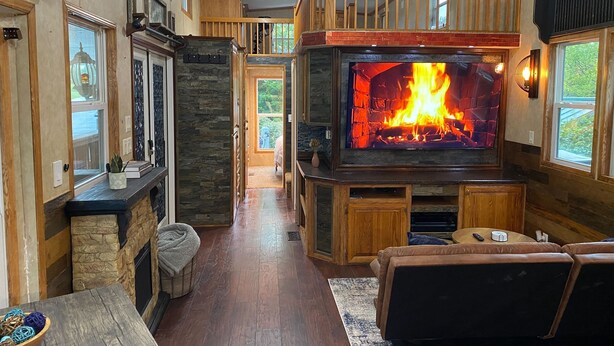 Ein gemütliches Wohnzimmer mit Kamin, Holzmöbeln und einer Wand aus Stein.