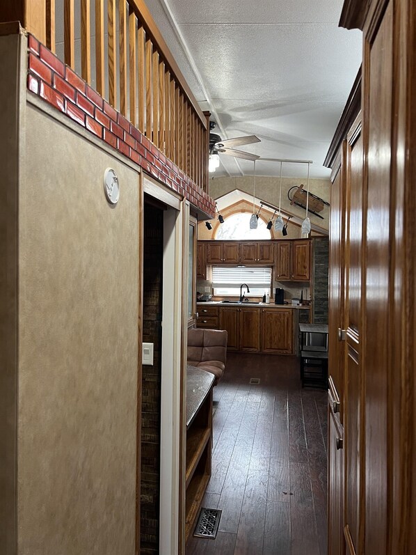 A compact RV kitchen with wooden cabinets, a built-in bench, and a window with blinds.