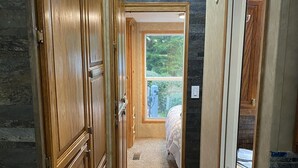 Ein schmales Dielenkorridor mit Holzausbau und Teppichboden, der zu einem Schlafzimmer mit Fenster führt.
