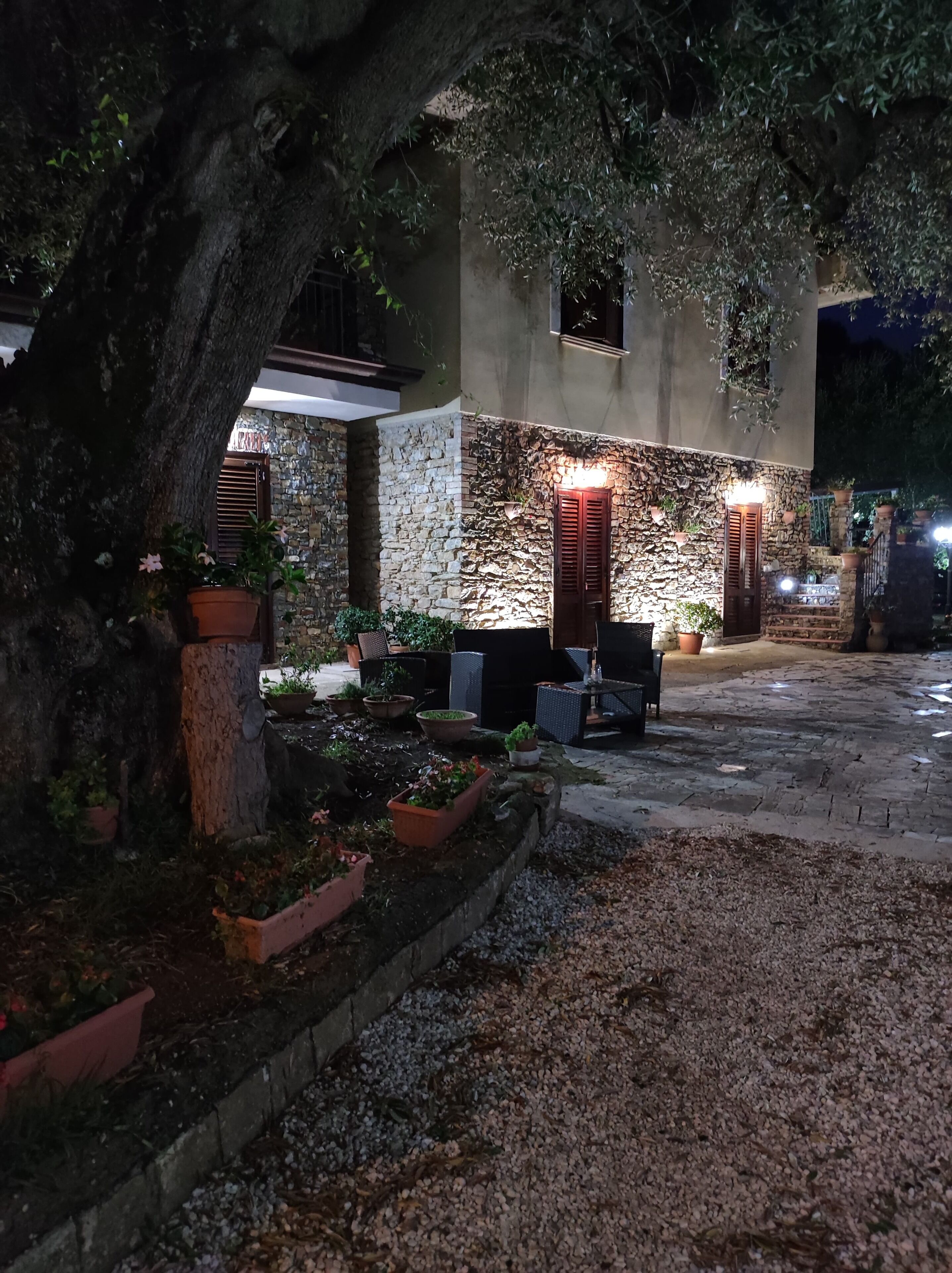 A stone building with a courtyard, outdoor seating, and potted plants.