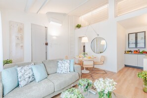 A modern living room with a grey sofa, a dining table with chairs, a kitchen area with cabinets, and a large mirror. - Letizia Loft in Lucca (Lucca)