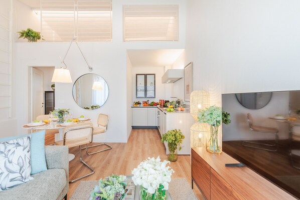 A modern living room with a sofa, dining table, and kitchen in the background. - Letizia Loft in Lucca (Lucca)