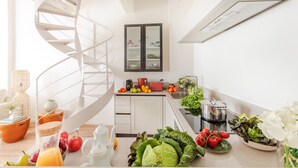 A modern kitchen with a spiral staircase, a built-in fridge, and a variety of fresh produce on the counter. - Letizia Vista in Lucca (Lucca)