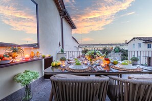 A dining table set for a meal with a sunset view, outdoor seating, and a balcony railing. - Letizia Mirror in Lucca (Lucca)