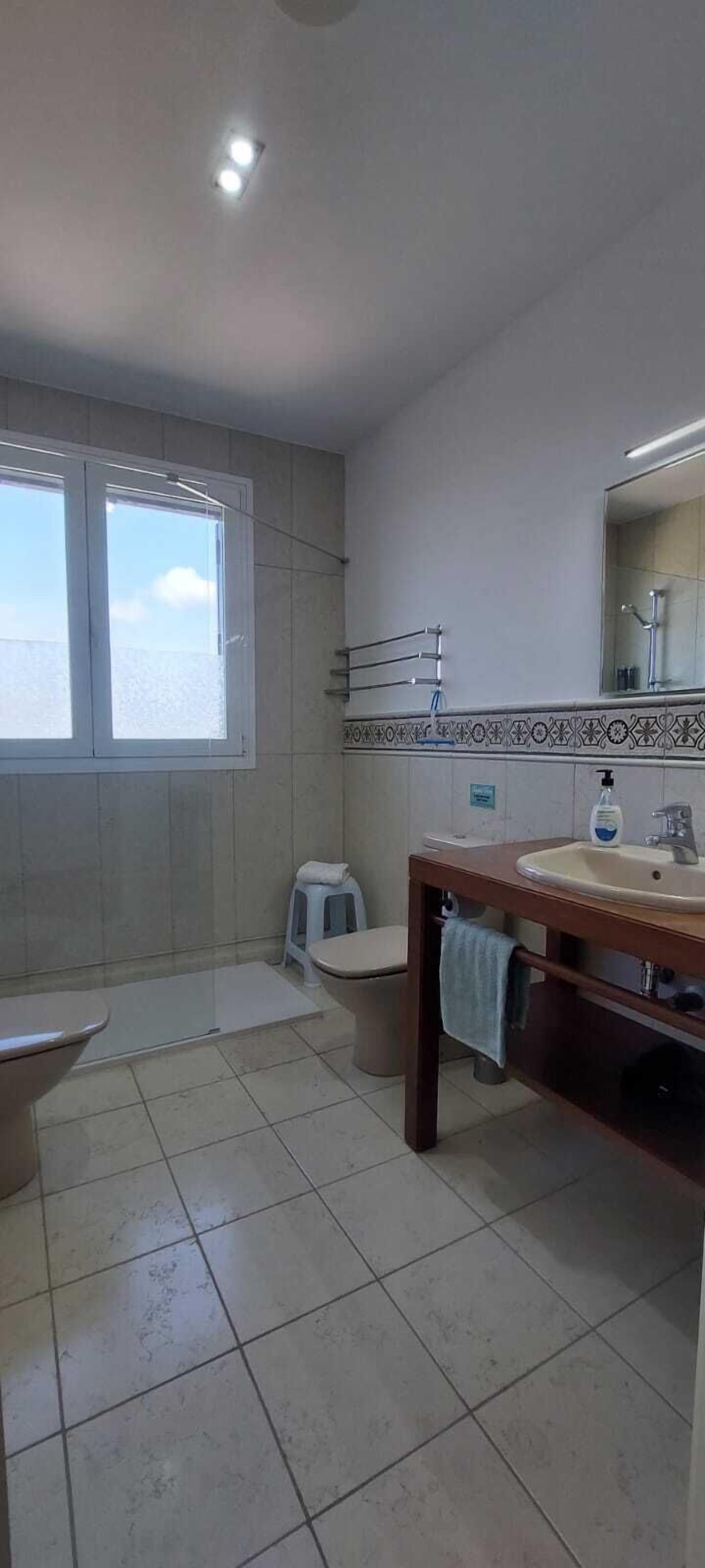 Un baño con inodoro, lavamanos, espejo y ventana.